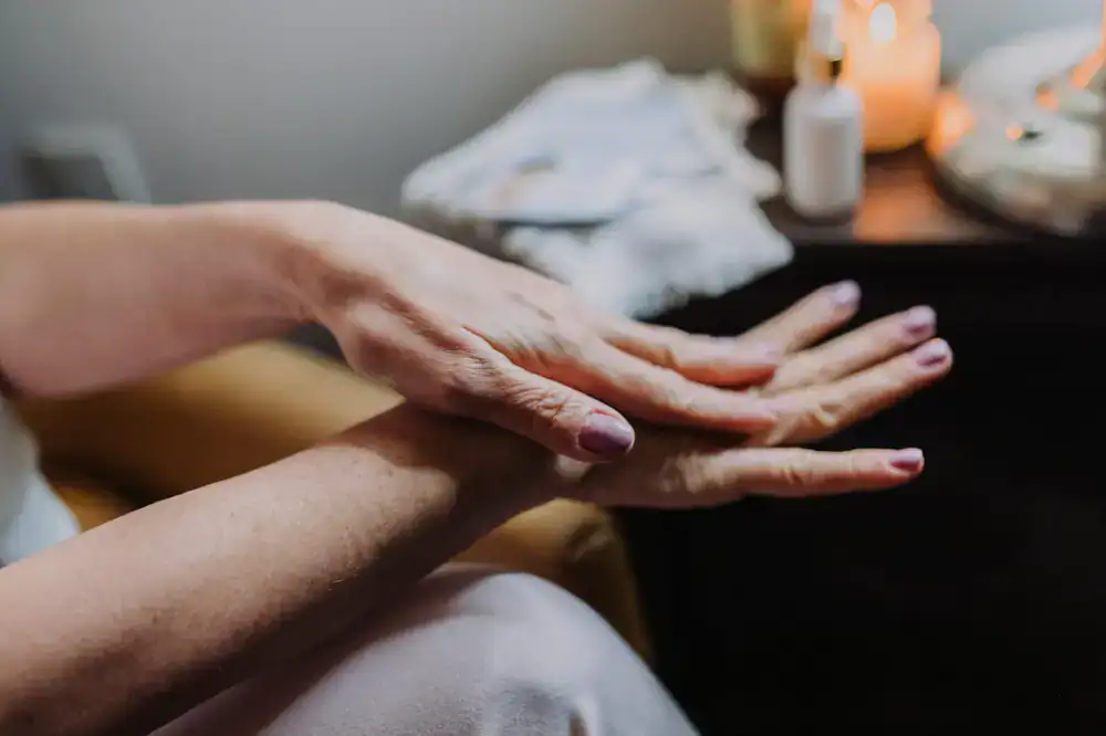 A happy client receiving a gentle hand massage during an at-home manicure